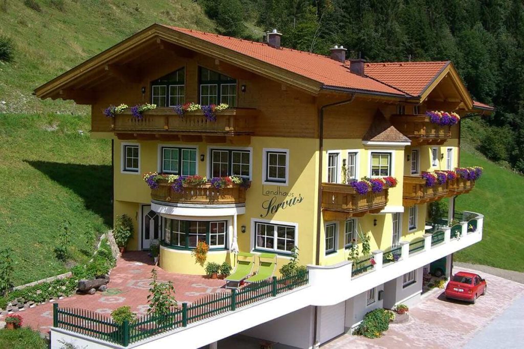 Gemütliches Landhaus Servus in Viehhofen, umgeben von Natur, mit Balkonen und Blumen.