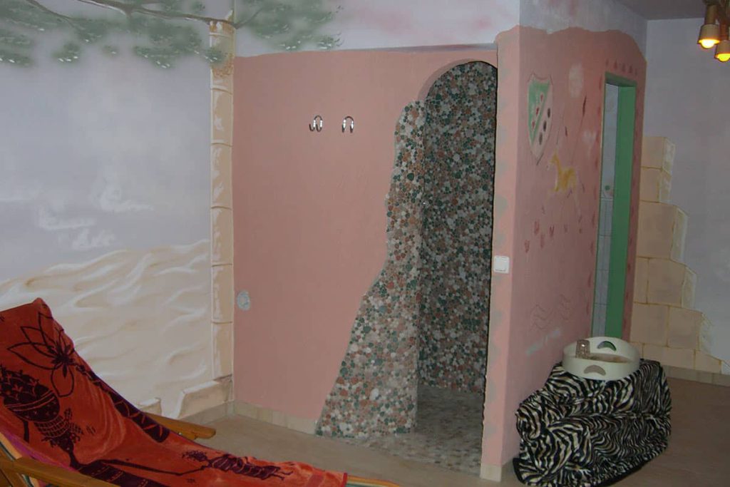 Bunt gestalteter Raum mit Liegestuhl und begehbarer Dusche im Landhaus Servus.